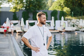 Lifeguard smiling and supervising swimming pool on a sunny day
