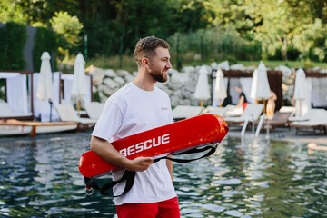 Lifeguard holding rescue equipment by the poolside