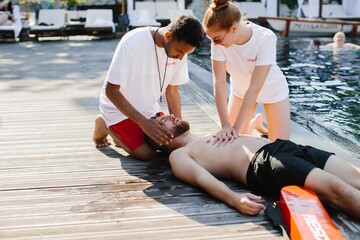 Lifeguards performing cpr on unconscious swimmer by poolside