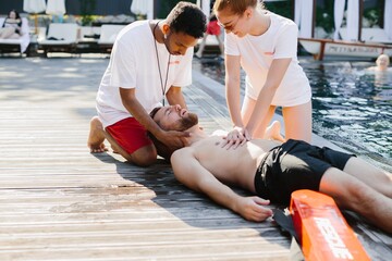 Lifeguards performing cpr on unconscious man at poolside