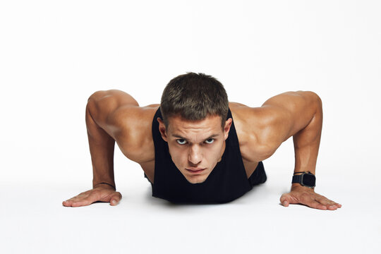 Male athlete executing push ups in a sleek studio setting, highlighting precision and dedication, isolated against white background. Ideal for fitness campaigns and motivational marketing materials.