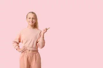 Gordijnen Happy teenager girl pointing at something on pink background © Pixel-Shot