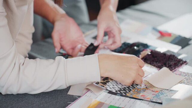 Costumer carefully comparing black textile sample against fair skin tone during creative design selection session, analyzing color compatibility and texture among various fabric swatches