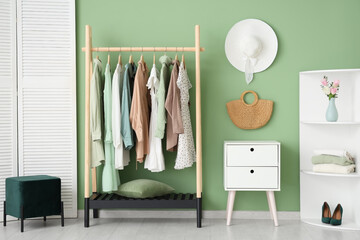 Interior of stylish dressing room with clothes rack, folding screen and shelving unit