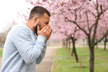 Sick young man suffering from allergy outdoors