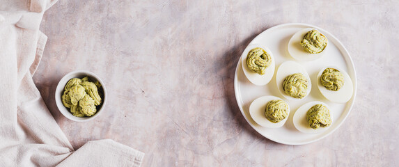 Avocado deviled eggs for appetizer on plate on table top view web banner