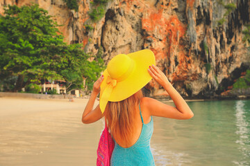 tourist with yellow straw hat stands at Railay beach, Krabi, Thailand
