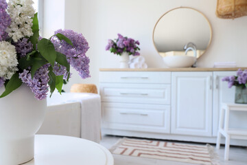 Vase with lilac flowers on table in bathroom, closeup