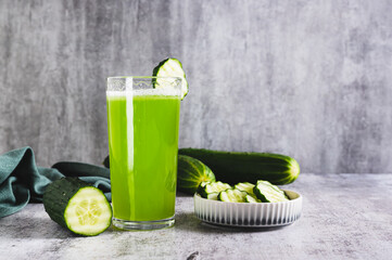 Fresh cucumber juice in a glass and cucumber pieces in a bowl on the table