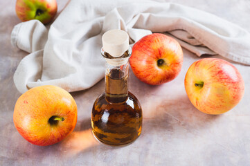 Fermented apple cider vinegar in glass bottle and fruits on table