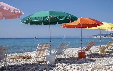 summer, Nice, France ,French Riviera, Colorful beach umbrellas and chairs on pebble beach