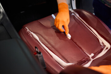 Cleaning a Luxury Car Seat with a Detail Brush and Foam for Maintaining Its Appearance