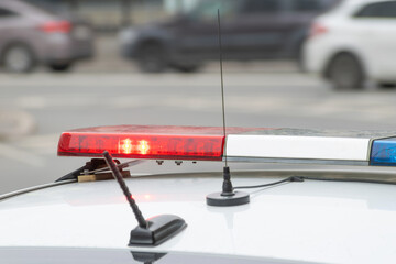 red and blue flashing light on a police car and cars passing by in front of it out of focus. selected focus.