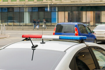 red and blue flashing light on a police car and cars and passersby passing in front of it out of...