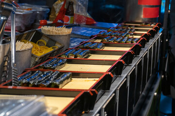 Kimbap rolls in vibrant street food style, colorful night lighting, traditional Korean cuisine preparation at Seoul, South Korea, Myeongdong Market