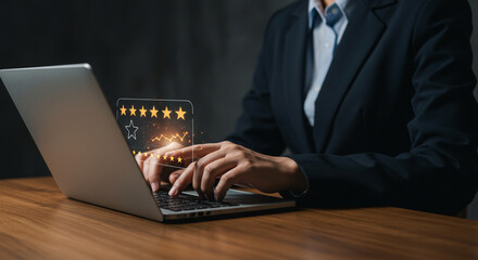 A person in a suit typing on a laptop with a five star rating graphic overlayed on the screen view