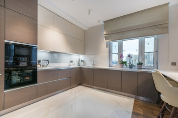 Modern interior design of the kitchen in the apartment. Roman curtain on the window. .The facade of...