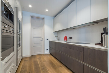 Modern kitchen interior with built-in appliances. The kitchen set is decorated with white and gray panels.