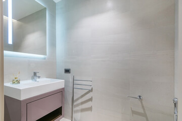 Laconic interior design of a bathroom decorated with white tiles.  A square mirror with...