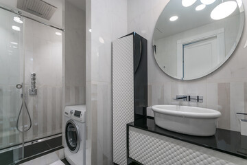 Elegant bathroom interior design. Stylish furniture, shower cabin. A washing machine is installed.