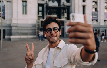 stylish influencer captures selfie with historic landmark in the background. His relaxed expression...