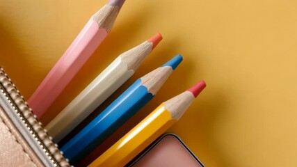 Colorful pencils in a zippered pouch with an eraser on a warm yellow background shot from above with copy space - Powered by Adobe