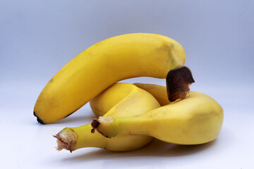 Cluster of four ripe bananas arranged in a slightly overlapping formation on a white studio...