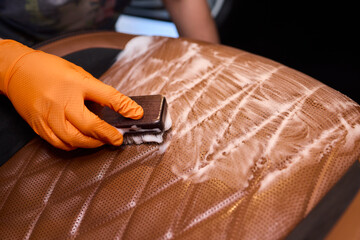 Cleaning a Luxury Car Seat with a Detail Brush and Foam for Maintaining Its Appearance