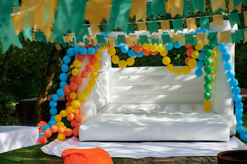 Outdoor party setup with white inflatable trampoline and balloons. Perfect for kids' celebrations in nature.