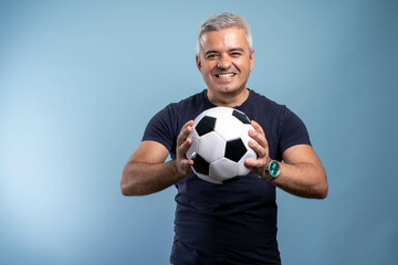 Excited mature man in casual blue t-shirt posing isolated on blue background studio portrait....