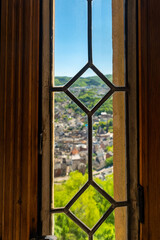 View from an ancient window overlooking a charming hillside village on a bright sunny day