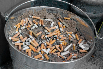 cigarettes stubbed out in bucket of sand outside pub