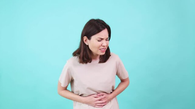 Woman suffering from abdominal pain on turquoise background