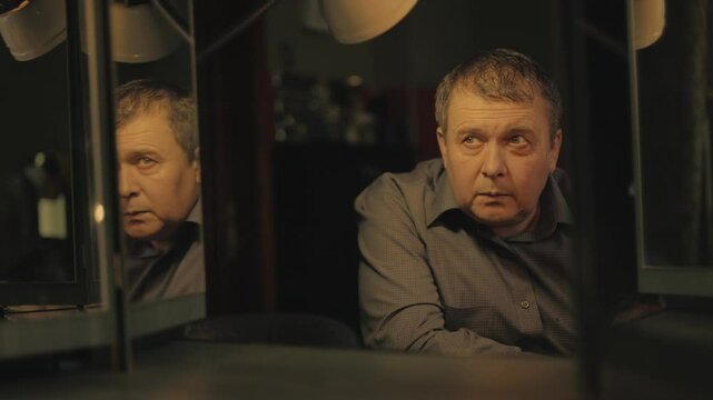 Reflection in the mirror of a man, mental problems.Emotions: stress, anger, bipolar disorder.The man is stressed and talking to himse.A dark room.Split personality