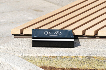 a device for wireless charging of electronic gadgets is installed near a bench in a city park