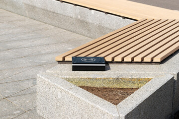 a device for wireless charging of electronic gadgets is installed near a bench in a city park