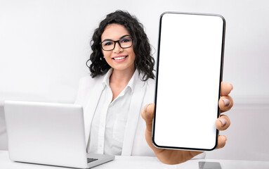 Female doctor showing big smartphone with blank screen, sitting in office at workplace, closeup,...