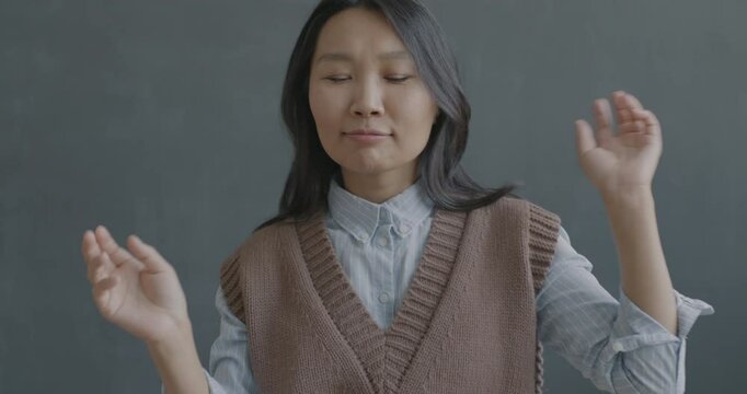 Slow motion portrait of young Asian woman dancing looking at camera on black color background. Happy people and entertainment concept.