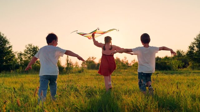 Children Boy, girl play with toy kite. Children toy plane. Kite flies in hands of child in summer in park under sun. Child's dream of flying concept, child runs across field at sunset with kite, sky