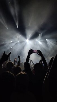 Clapping hands of people at a concert under spotlights.