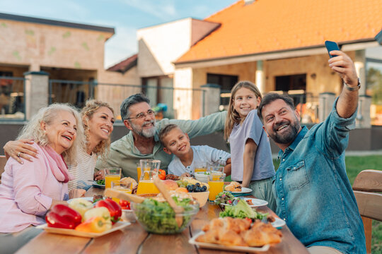 Happy family taking selfie while having lunch together in the backyard