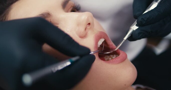 Close-up of dental examination, dentist using tools to examine and treat patient's teeth in a clinical setting. Concept dental care, oral hygiene, professional treatment, patient examination.
