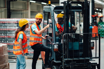 Warehouse workers discussing logistics near forklift in bottling plant