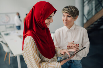 Two businesswomen using digital tablet in modern office