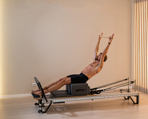 A man doing Pilates on a reformer. 