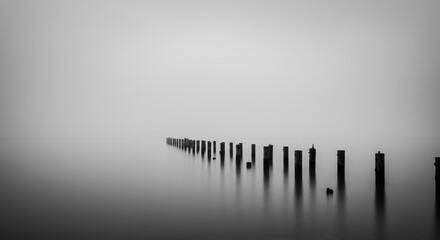 Minimalist misty lake long exposure wooden posts black white