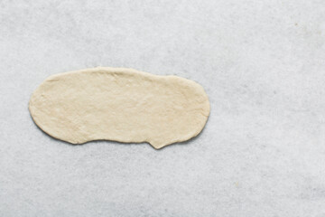 Overhead view of bagel dough being shaped on a white marble countertop, top view of shaping homemade bagels, process of making bagels