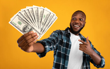 Happy Black Man Holding Money Cash Pointing Finger At Dollar Banknotes In His Hand Standing Over...