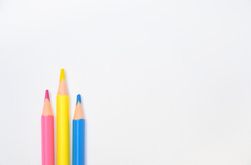 Three vibrant pencils lie on a clean white surface, symbolizing creativity, education, and back-to-school design ideas. Ideal for learning, stationery, or artistic concepts.