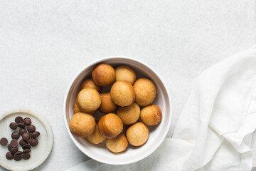 Overhead view of donut holes on a white bowl, top view of homemade doughnut holes on a white background, process of making doughnuts